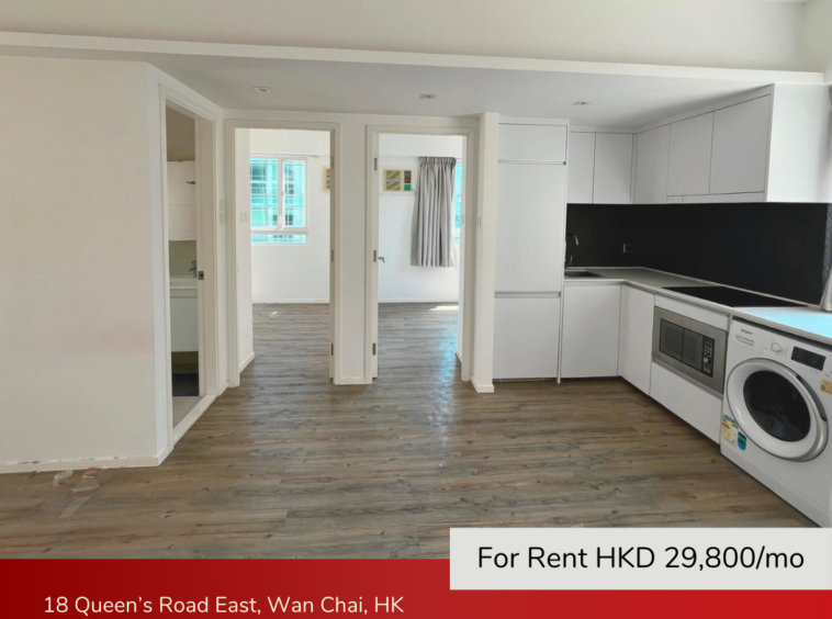 Open living room with integrated kitchen, white cabinetry, and wood flooring